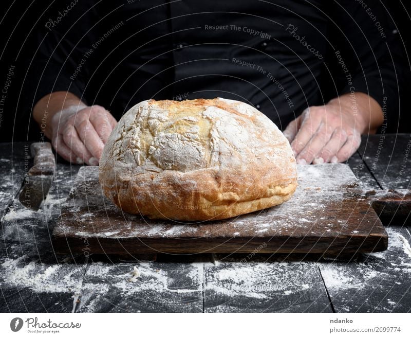 rund gebackenes hausgemachtes Brot Teigwaren Backwaren Messer Tisch Küche Beruf Koch Hand Holz Essen machen dunkel frisch braun schwarz weiß Tradition