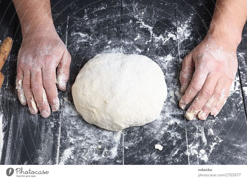 gekneteter Hefeteig aus Weizenweißmehl Teigwaren Backwaren Brot Ernährung Tisch Küche Koch Mensch Mann Erwachsene Hand Holz machen frisch schwarz Tradition