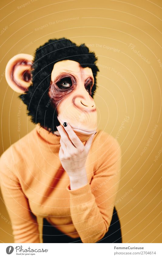 Woman with monkey mask posing against a yellow background feminin Frau Erwachsene 1 Mensch 18-30 Jahre Jugendliche 30-45 Jahre Freude lustig Maske Karneval