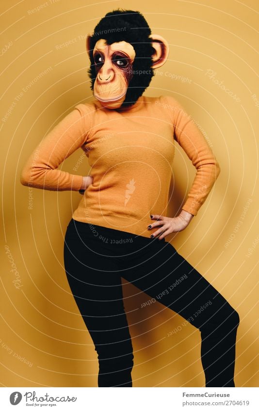 Woman with monkey mask posing against a yellow background feminin Frau Erwachsene 1 Mensch 18-30 Jahre Jugendliche 30-45 Jahre Freude Affen Schimpansen