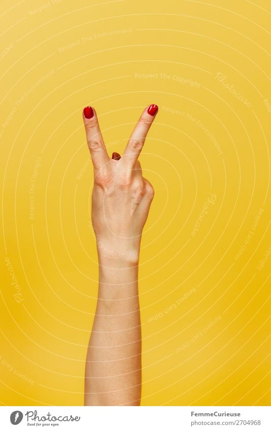 Hand signal for peace against a yellow background feminin Frau Erwachsene 1 Mensch 18-30 Jahre Jugendliche 30-45 Jahre Kommunizieren Frieden Zeichen