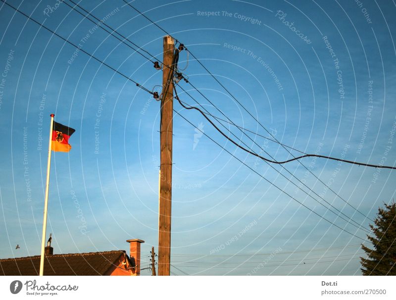 im Niemandsschland Himmel Stadtrand Haus Dach Schornstein Zeichen blau Identität Hochspannungsleitung Fahnenmast Bundesadler Nationalflagge Wohnsiedlung