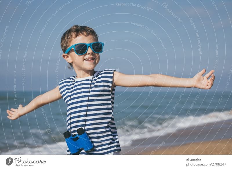 Ein glücklicher kleiner Junge, der tagsüber am Strand spielt. Er ist mit einer Matrosenweste bekleidet. Ein Kind, das sich draußen amüsiert. Konzept eines Matrosen im Urlaub.