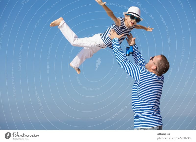 Vater und Sohn spielen zur Tageszeit am Strand. Sie sind in Matrosenwesten gekleidet. Konzept der Matrosen im Urlaub und der freundlichen Familie. Lifestyle