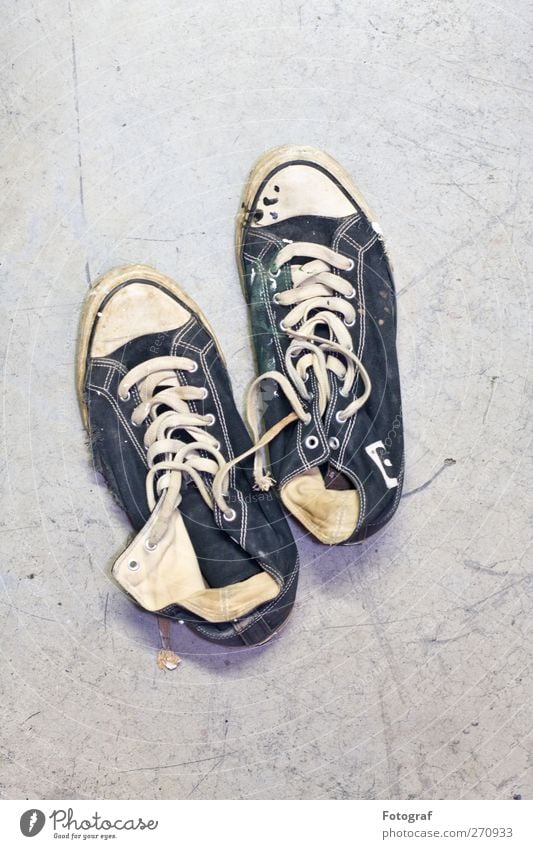 Treter. Schuhe Turnschuh blau schwarz weiß Chucks kaputt Schuhbänder Farbfoto Innenaufnahme Textfreiraum oben Hintergrund neutral Starke Tiefenschärfe