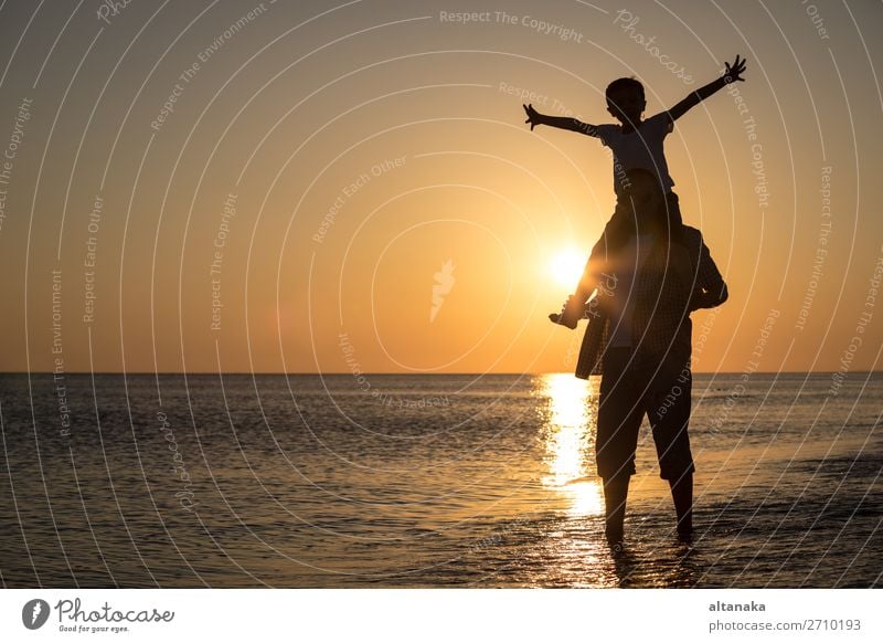 Vater und Sohn spielen zur Zeit des Sonnenuntergangs am Strand. Die Menschen haben Spaß im Freien. Konzept eines glücklichen Urlaubs und einer freundlichen Familie.