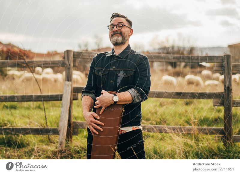 Erwachsener Mann mit Gitarrenkoffer Natur Musiker fallen stehen Wegsehen ländlich Zaun Lifestyle Mensch Sommer lässig akustisch gutaussehend Typ