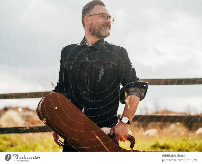 Erwachsener Mann mit Gitarrenkoffer Natur Musiker fallen stehen Wegsehen ländlich Zaun Lifestyle Mensch Sommer lässig akustisch gutaussehend Typ