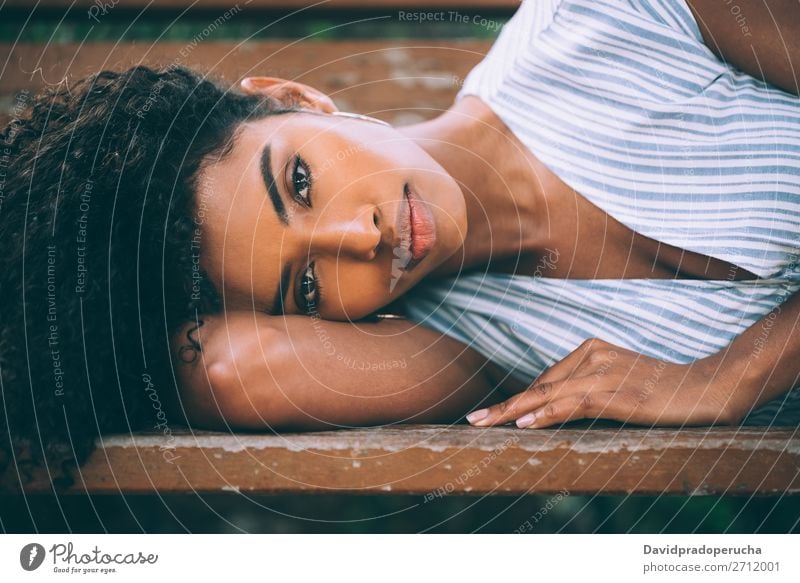 Schöne junge schwarze Frau, die sich auf einem Stuhl in einem Park niederlässt. Beautyfotografie Nahaufnahme Porträt multiethnisch Afrikanisch