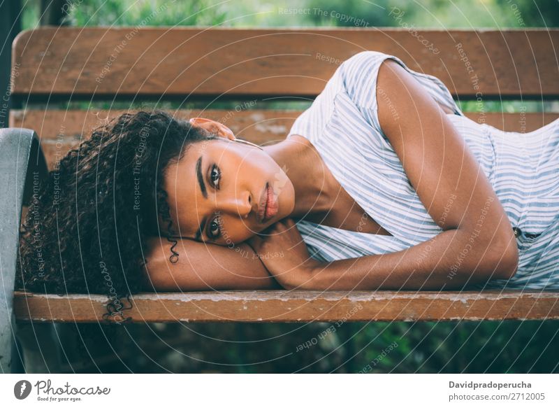 Schöne junge schwarze Frau, die sich auf einem Stuhl in einem Park niederlässt. Beautyfotografie Nahaufnahme Porträt multiethnisch Afrikanisch