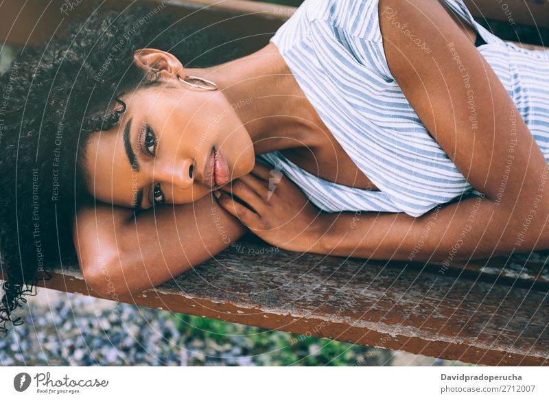 Schöne junge schwarze Frau, die sich auf einem Stuhl in einem Park niederlässt. Beautyfotografie Nahaufnahme Porträt multiethnisch Afrikanisch