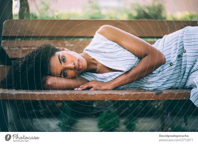 Schöne junge schwarze Frau, die sich auf einem Stuhl in einem Park niederlässt. Beautyfotografie Nahaufnahme Porträt multiethnisch Afrikanisch