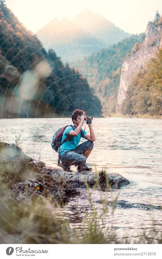 Junger Tourist mit Rucksack schaut durch ein Fernglas. Lifestyle Leben Freizeit & Hobby Ferien & Urlaub & Reisen Ausflug Sommer Berge u. Gebirge Mensch