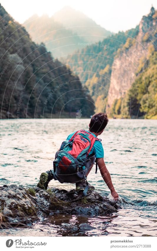 Kleiner Junge mit Rucksack, der auf einem Felsen über einem Fluss sitzt. Lifestyle Körper Leben Freizeit & Hobby Ferien & Urlaub & Reisen Ausflug Sommer