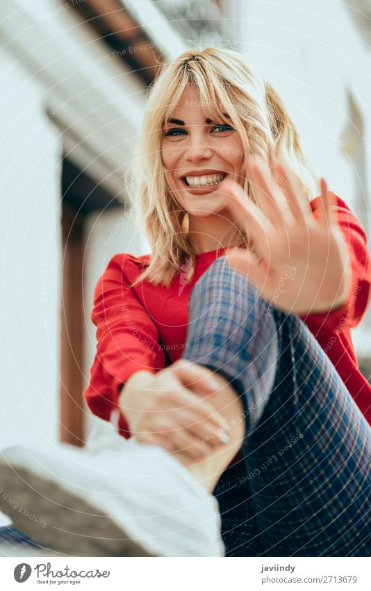 Glückliche Frau, die im Freien sitzt und ihre Hand in die Nähe der Kamera legt. Lifestyle Stil schön Haare & Frisuren Mensch feminin Junge Frau Jugendliche