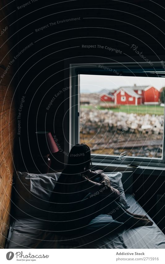 Frau auf dem Bett schaut aus dem Fenster. Haus Morgen Mensch dunkel Erholung ruhen Freizeit & Hobby genießend Aussicht Dorf rustikal ländlich Gemütlichkeit