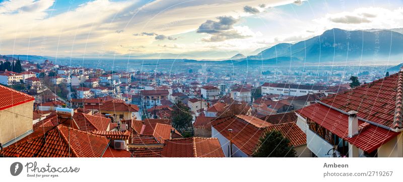 Griechisches Stadtabendpanorama mit Häusern mit roten Dächern im Tal mit Bergen im Sonnenuntergang, Kalabaka, Thessalien, Griechenland Herbst schön Gebäude