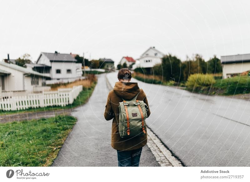 Frau auf der Dorfstraße Straße Ferien & Urlaub & Reisen Tourismus Tourist laufen Mensch Reisender Rucksack ländlich rustikal Haus Hütten matt grau Tag friedlich