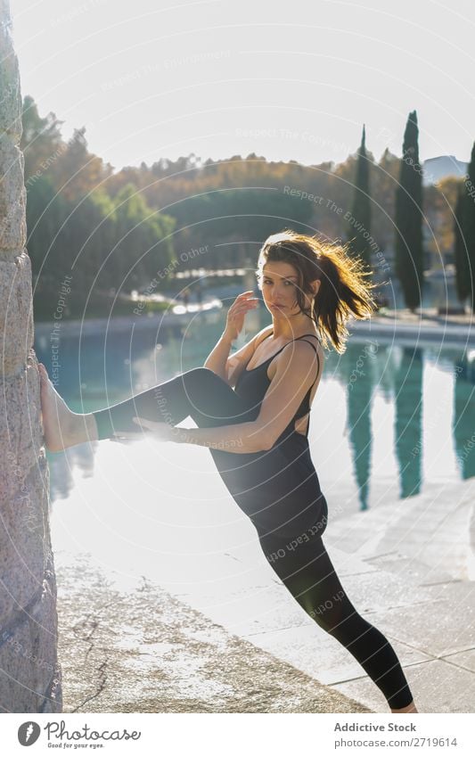 Frau, die ihre Beine im Park ausstreckt. sportlich hübsch Jugendliche heiter strecken Dehnübung Teich Großstadt schön Sport Lifestyle Stil attraktiv Pose