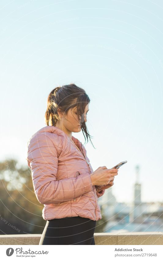 Hübsche Frau steht mit Smartphone auf der Straße. hübsch PDA Park Glück schön Telefon Jugendliche Mobile Lächeln attraktiv Lifestyle Natur Außenaufnahme heiter