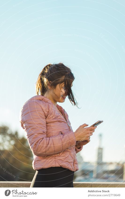 Hübsche Frau steht mit Smartphone auf der Straße. hübsch PDA Park Glück schön Telefon Jugendliche Mobile Lächeln attraktiv Lifestyle Natur Außenaufnahme heiter