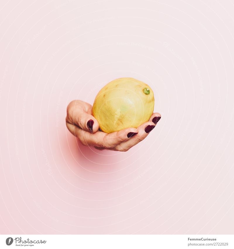 Hand of a woman with lemon in front of pink background Lebensmittel Ernährung Frühstück Mittagessen Büffet Brunch Picknick Bioprodukte Vegetarische Ernährung