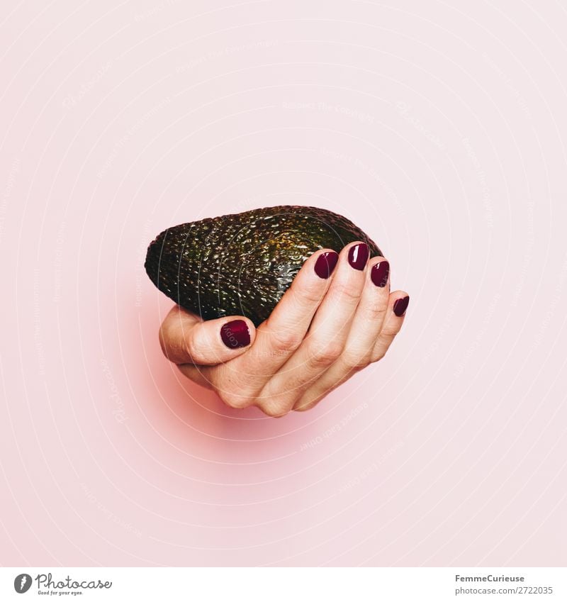 Hand of a woman with avocado in front of pink background Lebensmittel Ernährung Frühstück Mittagessen Abendessen Büffet Brunch Picknick Bioprodukte