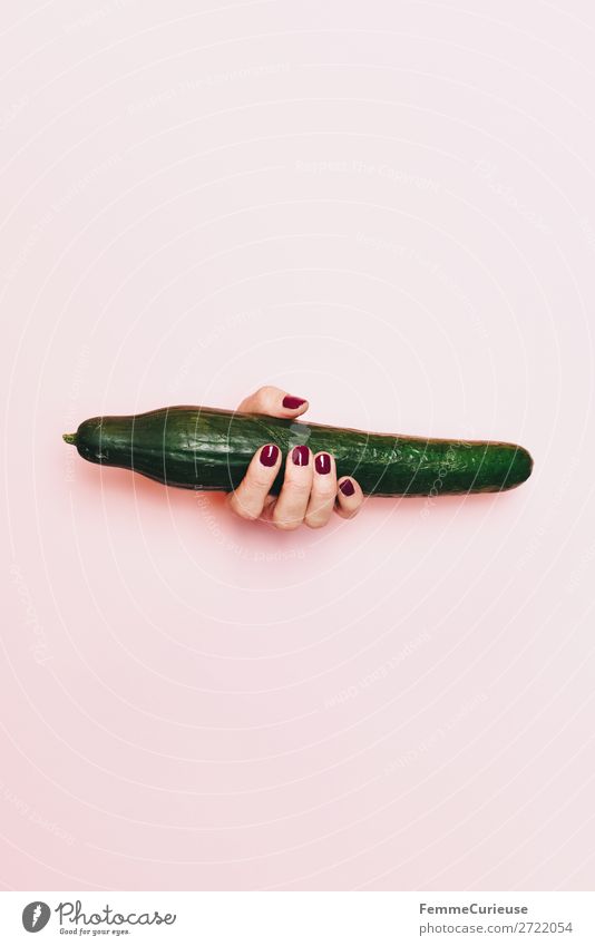 Hand of a woman with cucumber in front of pink background Lebensmittel Ernährung Frühstück Mittagessen Picknick Bioprodukte Vegetarische Ernährung Diät feminin