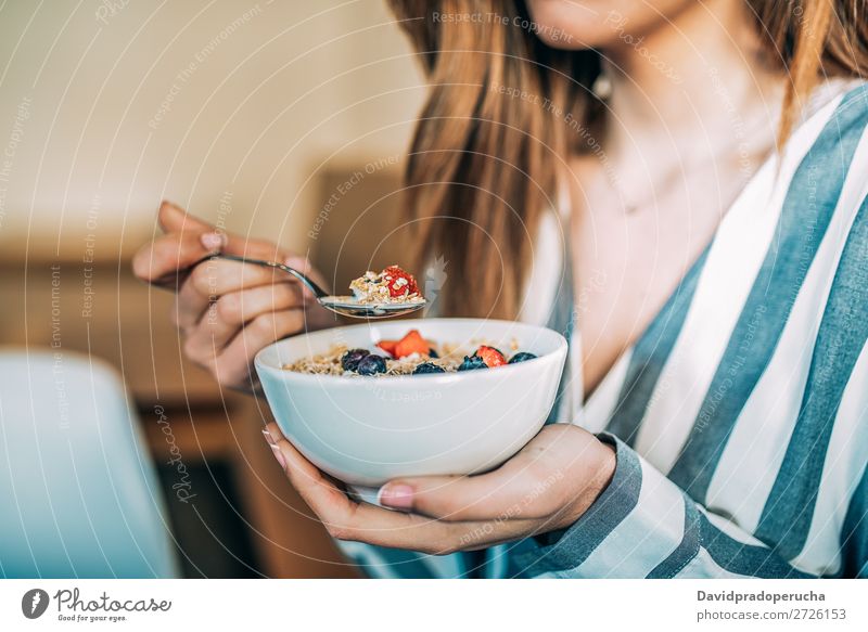 Getreidefrau aus der Nähe beim Essen von Hafer und Früchten Schüssel zum Frühstück Schalen & Schüsseln Frau Müsli Haferbrei Hand Feldfrüchte anonym unkenntlich