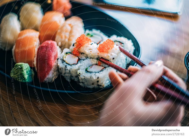 Getreidefrau beim Sushi essen Frau Hand Lebensmittel Soja maki Kalifornische Walze Essstäbchen Brötchen Feldfrüchte unkenntlich anonym Nahaufnahme Porträt Lachs