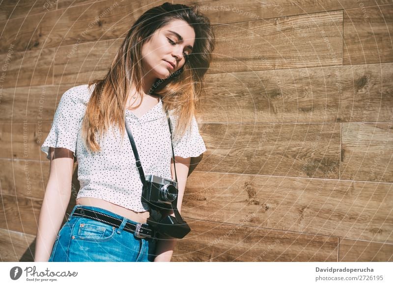 Schöne Frau mit alter Kamera, die an einer Holzwand steht. altehrwürdig Fotokamera retro Jugendliche schön Rolle Porträt Fotografie vereinzelt Beautyfotografie