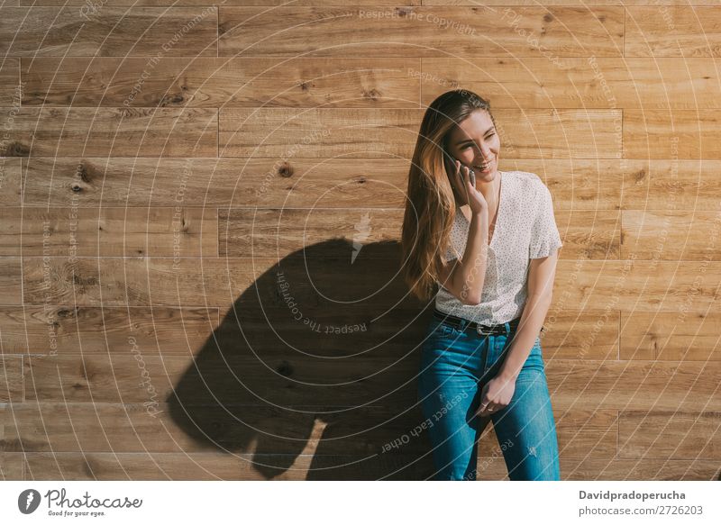 Glückliche Frau mit Smartphone an einer Holzwand PDA Telefon Mobile Mitteilung Gerät Lächeln Wegsehen Porträt Hintergrundbild Sommer Wand Halt klug Jugendliche