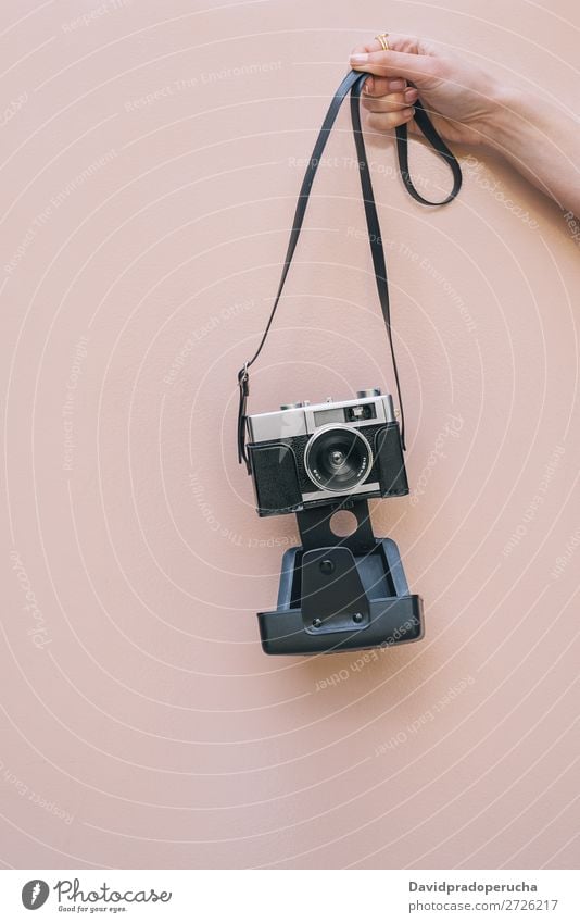 Hand haltend eine Vintage-Kamera isoliert an der rosa Wand Arme Fotokamera altehrwürdig retro vereinzelt Studioaufnahme Halt Freizeit & Hobby