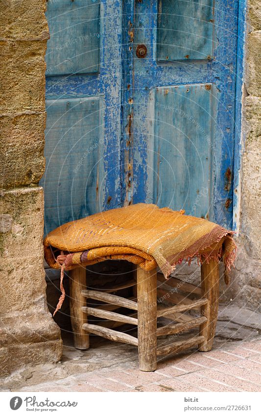 Kleiner Hocker mit Decke, steht vor blauer Tür, in der Medina. Ferien & Urlaub & Reisen Tourismus Ausflug Sightseeing Städtereise Stuhl Haus Mauer Wand hocken