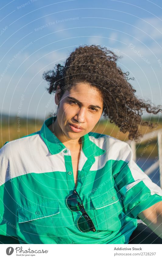 Lockenförmige Frau, die im Sonnenlicht auf der Natur posiert. Sommer genießen Körperhaltung Menschliches Gesicht Landschaft Farbe Porträt lockig ruhig