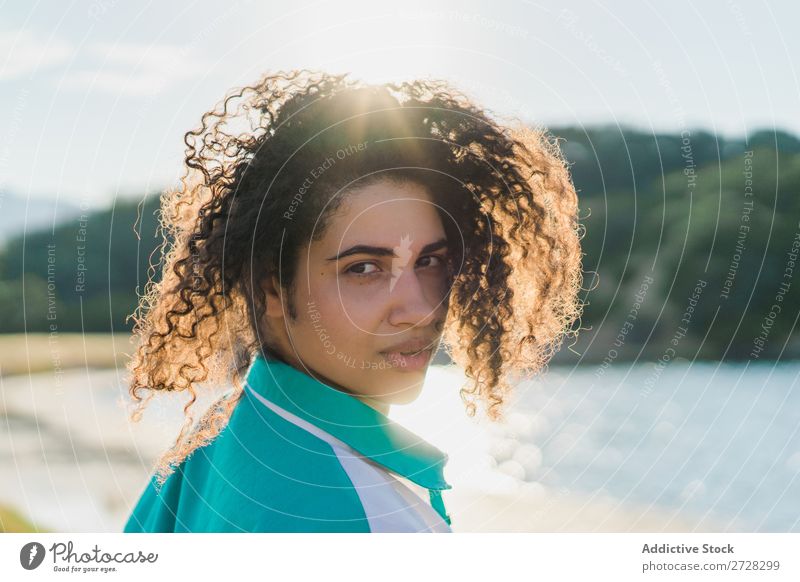 Lockenförmige Frau, die im Sonnenlicht auf der Natur posiert. Sommer genießen Körperhaltung Menschliches Gesicht Landschaft Farbe Porträt lockig ruhig