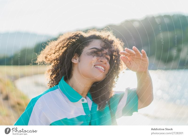 Lockenförmige Frau, die im Sonnenlicht auf der Natur posiert. Sommer genießen Körperhaltung Menschliches Gesicht Landschaft Farbe Porträt lockig ruhig