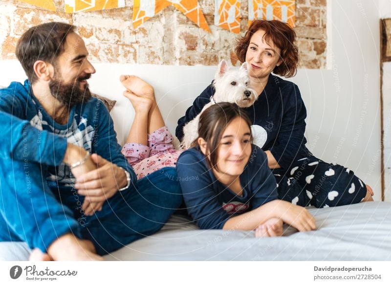 Ein Paar entspannt zu Hause im Bett mit seiner kleinen Tochter und dem Hund. Zuneigung Schlafzimmer Ehefrau Ehemann Kind Haustier Welpe Mama Papa Eltern Vater