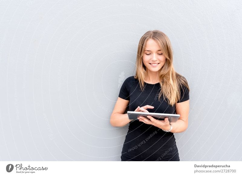 Glückliche junge Frau auf dem Tablett an der Wand vereinzelt blond Tablet Computer Technik & Technologie Kaffee Jugendliche schwarz Kleid Beautyfotografie