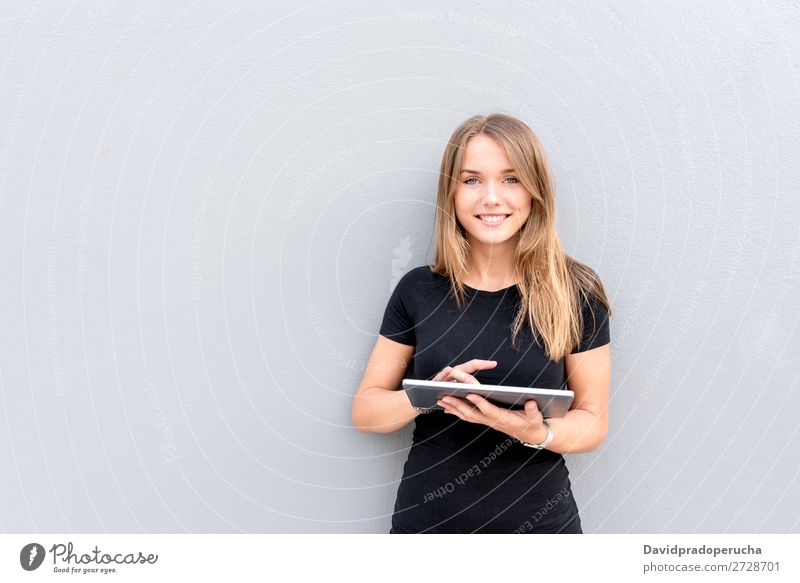 Glückliche junge Frau auf dem Tablett an der Wand vereinzelt blond Tablet Computer Technik & Technologie Kaffee Jugendliche schwarz Kleid Beautyfotografie