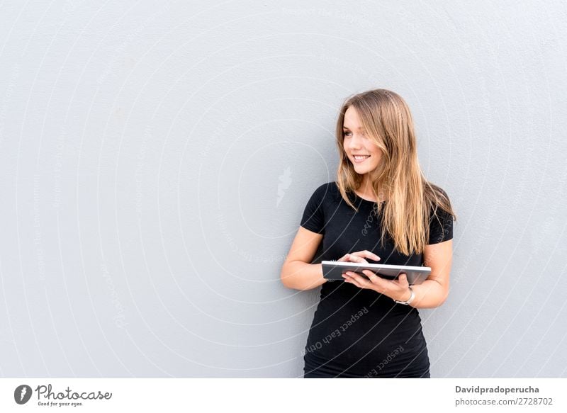 Glückliche junge Frau auf dem Tablett an der Wand vereinzelt blond Tablet Computer Technik & Technologie Kaffee Jugendliche schwarz Kleid Beautyfotografie