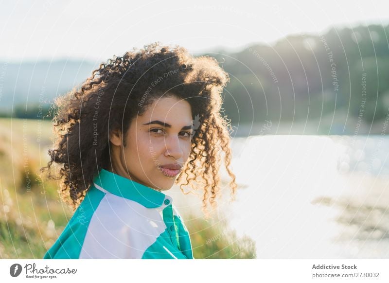 Lockenförmige Frau, die im Sonnenlicht auf der Natur posiert. Sommer genießen Körperhaltung Menschliches Gesicht Landschaft Farbe Porträt lockig ruhig