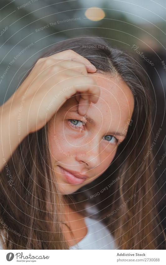 Hübsche Frau, die das Haar anpasst. hübsch Jugendliche schön Behaarung ausrichten Blick in die Kamera Beautyfotografie Glas Fenster grüne Augen brünett