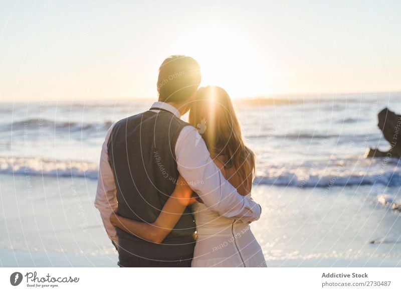 Umarmung des Hochzeitspaares bei Sonnenuntergang Paar Strand Sonnenlicht Genuss stehen umarmend Fröhlichkeit Liebe Beautyfotografie Zusammensein romantisch