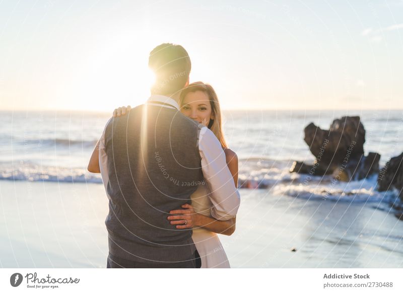 Zärtlich küssendes Brautpaar im Sonnenlicht Paar Hochzeit Strand umarmend Engagement Zufriedenheit Valentinsgruß Genuss verliebt Meereslandschaft stehen