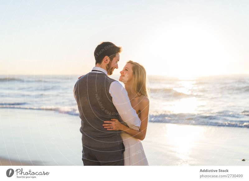 Zärtlich küssendes Brautpaar im Sonnenlicht Paar Hochzeit Strand umarmend Engagement Zufriedenheit Valentinsgruß Genuss verliebt Meereslandschaft stehen