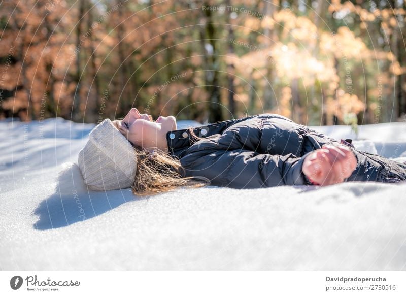 Junge süße Frau liegend spielend und schneesicher im Winter Schnee Porträt Jugendliche Glück Spielen lügen blond schön Mädchen Kaukasier Erwachsene Mode Haut