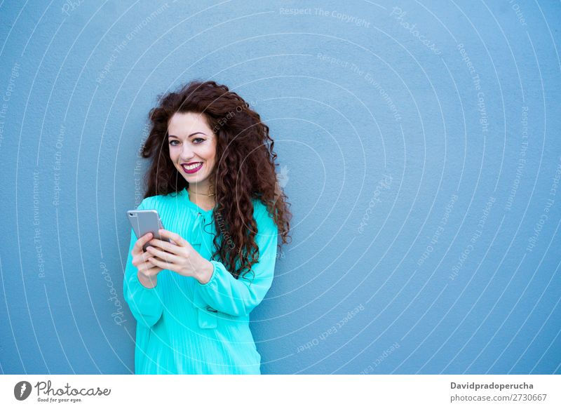 Glückliche junge Frau auf dem Handy an einer bunten Wand rothaarig Telefon Business Geschäftsfrau Technik & Technologie Mobile Lächeln Gesicht Beautyfotografie