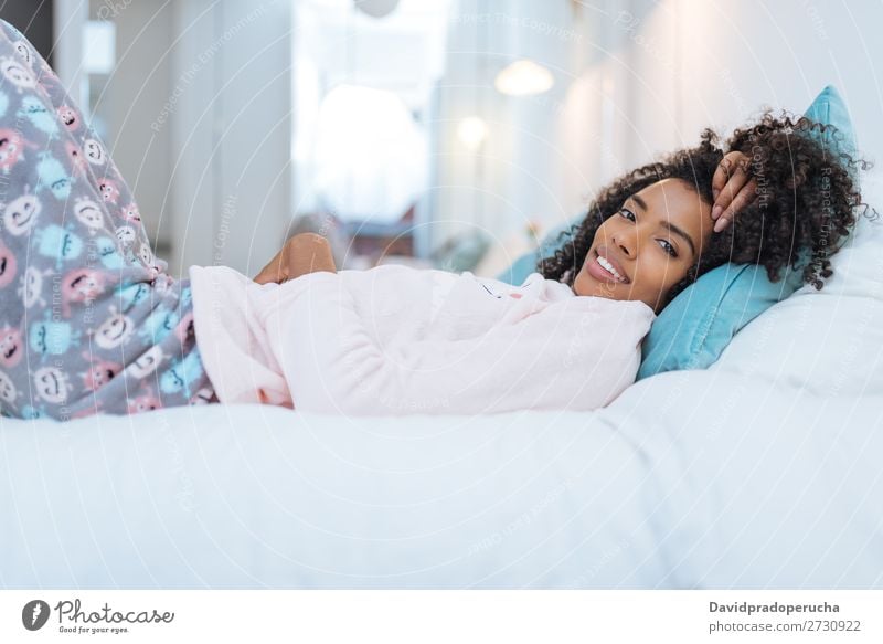 Fröhlich schöne junge schwarze Frau entspannte sich im Bett liegend. Lächeln Erholung wach niedlich gemütlich Winter Schlafanzug Pyjama kalt lügen abwärts