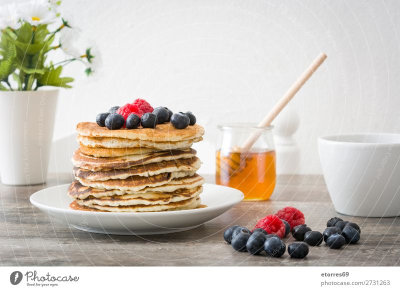 Honig in Pfannkuchen mit Himbeeren und Blaubeeren gießen. Bonbon Dessert Frühstück Beeren blau rot backen Lebensmittel Gesunde Ernährung Foodfotografie Speise